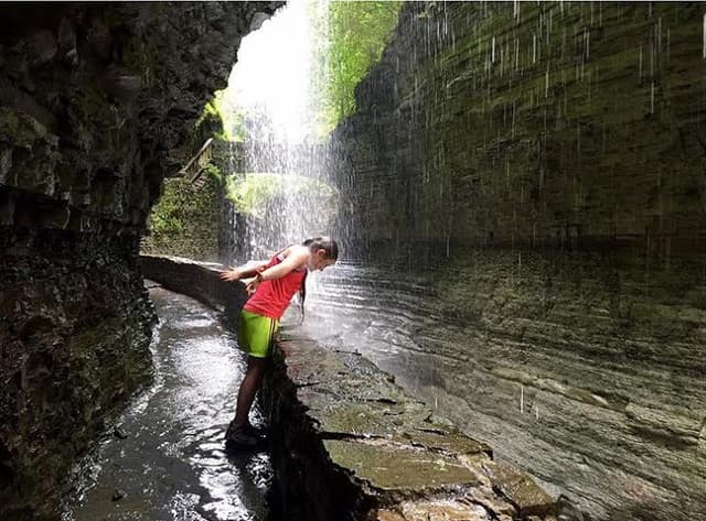 Person Walking Behind Waterfall